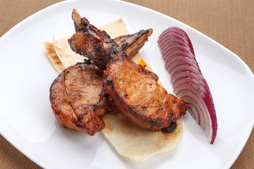 Grilled pork ribs served with pita and red onion