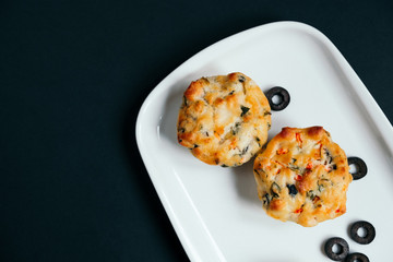 Cupcakes with spinach, cheese and vegetables on a black background. Healthy breakfast concept. Copy space