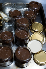 Chocolate spread in spoon with jar on dark background