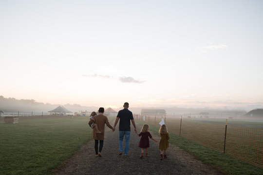 Family With Three Children Walking On Rural Road On Misty Morning