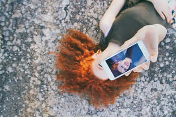 Adolescente pelirroja sacándose un selfie con su teléfono móvil 
