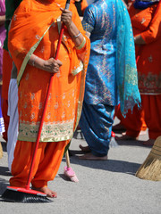 Barefoot women with long clothes sweep the way during the sikh c