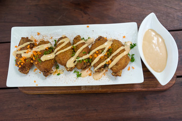 spicy chicken wings in white plate on wood table
