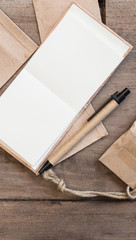 Blank notebook, pen and brown envelope on wooden table