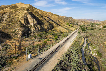 Straight line of railroad tracks lead through a valley in the Mojave Desert of California.