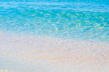 Fototapeta na wymiar Soft sea waves wash over golden sand in a beach. Blured natural background