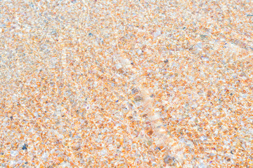 Soft sea waves wash over golden sand (shell rock) in a beach. Blured natural background.