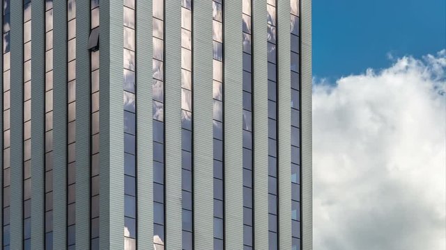 Timelapse of clouds reflecting onto the glass of a large office building