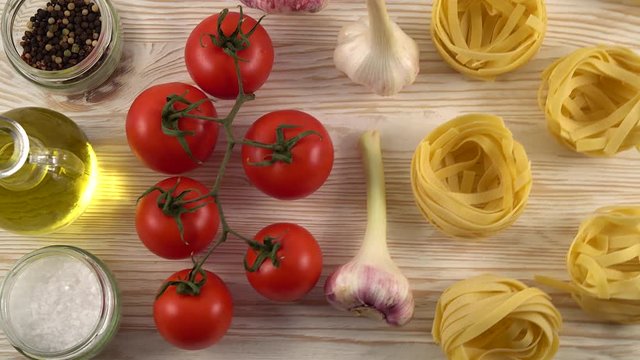 pasta, oil, tomatos and garlic on wooden background