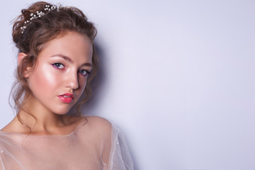 girl in the image of a bride with a wedding with makeup and hairstyle on a light background