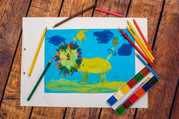 lion. child paint colorful color pencil drawing: Child draws of the funny lion on blue sky on wood background texture