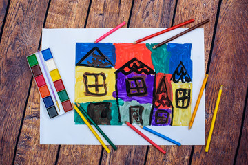 Child draws a pencil drawing of the house for family on wood background. New home. Top view. Family concept