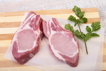 Raw pork chops, spices and basil on cutting board. Ready for cooking.