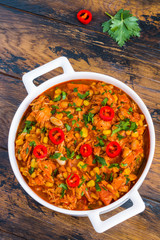 Hearty and healthy Southwest chicken and beans stew  in a white casserole on the wooden table, top view.