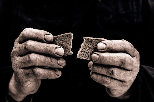 Dirty hands of a man clamped a piece of bread.

