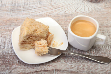Homemade Napoleon puff cake on plate and traditional espresso coffee isolated on white background. close-up.