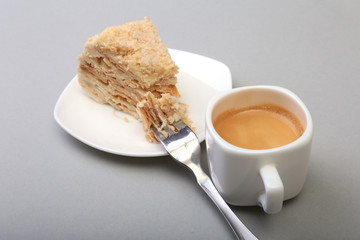 Homemade Napoleon puff cake on plate and traditional espresso coffee isolated on white background. close-up.