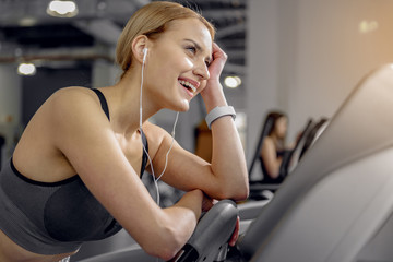 Fototapeta na wymiar Outgoing female listening music in fitness center