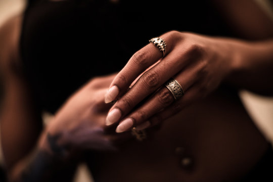 A closeup of a young, black woman putting on jewlery