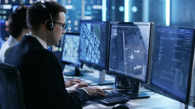In Government Agency System Surveillance Center Employees Trace Criminal with Help of GPS. Their Room is Full of Displays with Various Data on Them. Shot on RED EPIC-W 8K Helium Cinema Camera.