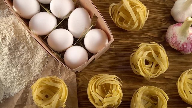 pasta, eggs, oil, tomatos, garlic and flour on wooden background