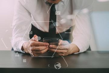 Obraz na płótnie Canvas close up of businessman working with smart phone on wooden desk in modern office with virtual icon diagram