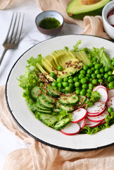Mix salad with cucumber, avocado, green peas and flax seeds on a marble background