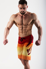 Fototapeta na wymiar Muscle male model in colorful shorts posing on white background. Studio shoot.