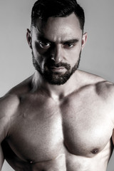 Fototapeta premium Portrait of muscle male model posing on grey background. Studio shoot.