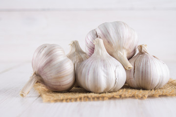 Garlic cloves and garlic bulb on a white wooden table.