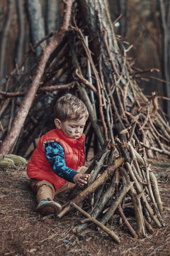 Cute little boy building a wooden shelter