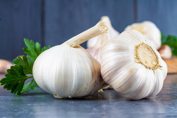 Garlic cloves and garlic bulb on a wooden board on a gray background.
