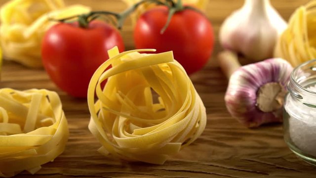 pasta, oil, tomatos and garlic on wooden background