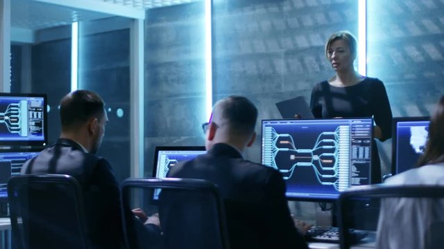 In The Government System Control Center. Female Supervisor with Laptop Holds Meeting For Her Team of Engineers. Shot on RED EPIC-W 8K Helium Cinema Camera.