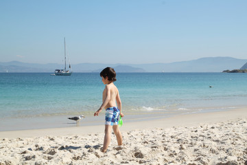 child in the beach looking to the sea