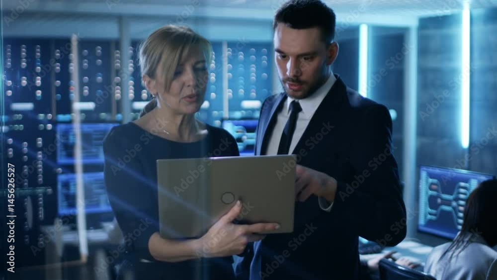 Aufkleber in system control room female and male top managers have discussion. in the background professional 