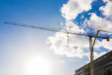 Building crane and building under construction against blue sky