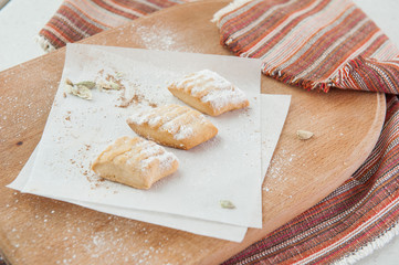 Fresh pastry with various fillings sprinkled with powdered sugar on the wooden board. Selective focus
