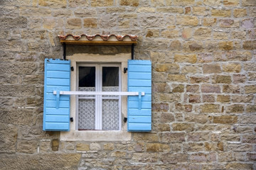 Fototapeta na wymiar Blue wooden window shutters on the old stone house