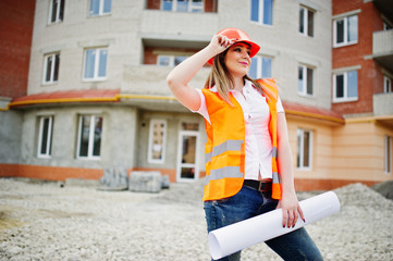 Engineer builder woman in uniform waistcoat and orange protective helmet hold business paper...