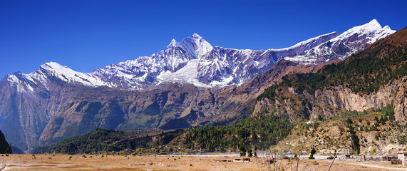 Dhaulagiri-Berg über dem Tal des Kali Gandaki-Flusses. Panoramablick vom Annapurna Circuit mit dem kleinen Dorf Larjung am Hang, Himalaya, Nepal, Asien