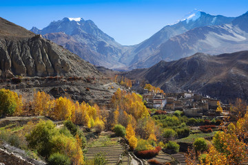 Thorong la Pass  between two high hills with snow tops, and Muktinath valley with local nepalese buddhist village, in the autumn. Horizontal view, Nepal, Annapurna Circuit; Himalaya mountains; Asia