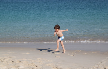 happy kid running in the beach in summer