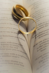 Wedding rings casting a heart shape on a book