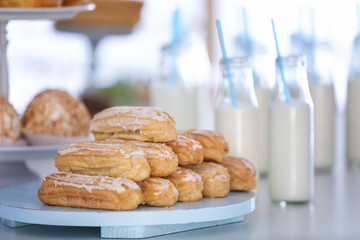 Delicious eclairs on wooden tray, closeup