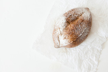 Fototapeta na wymiar A loaf of homemade bread in a paper on a white background with space for your text.