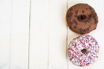 Delicious donuts on white wooden background