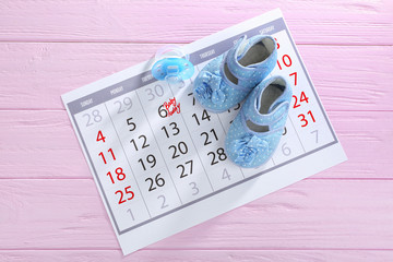 Fototapeta premium Calendar with baby booties on wooden background