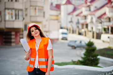 Engineer builder woman in uniform waistcoat and orange protective helmet hold business drawing paper roll against new building. Property living block theme.