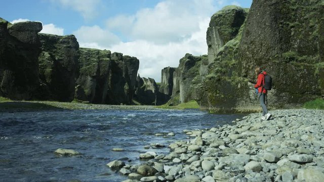 Woman hiker stops to fill up water bottle in river